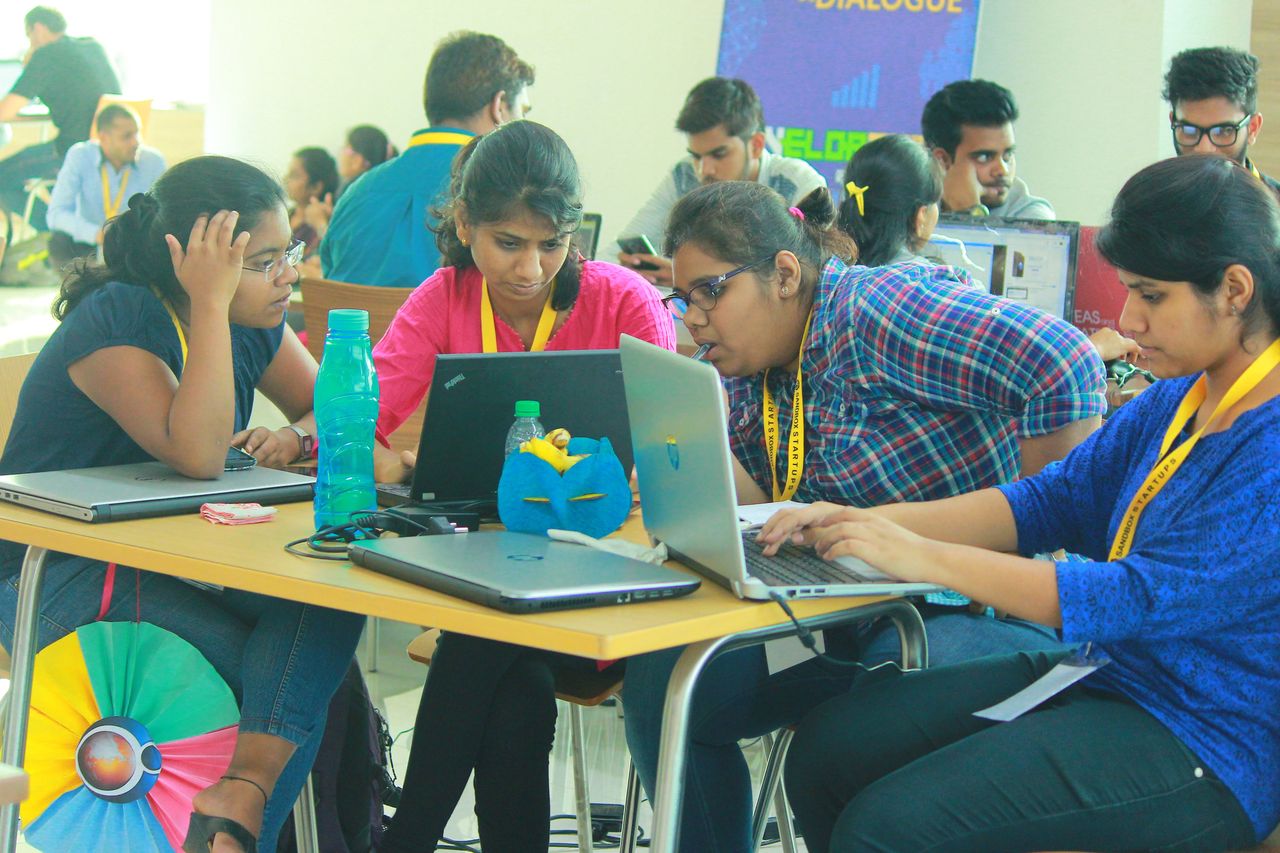 Participants working together on laptops at a table during an event