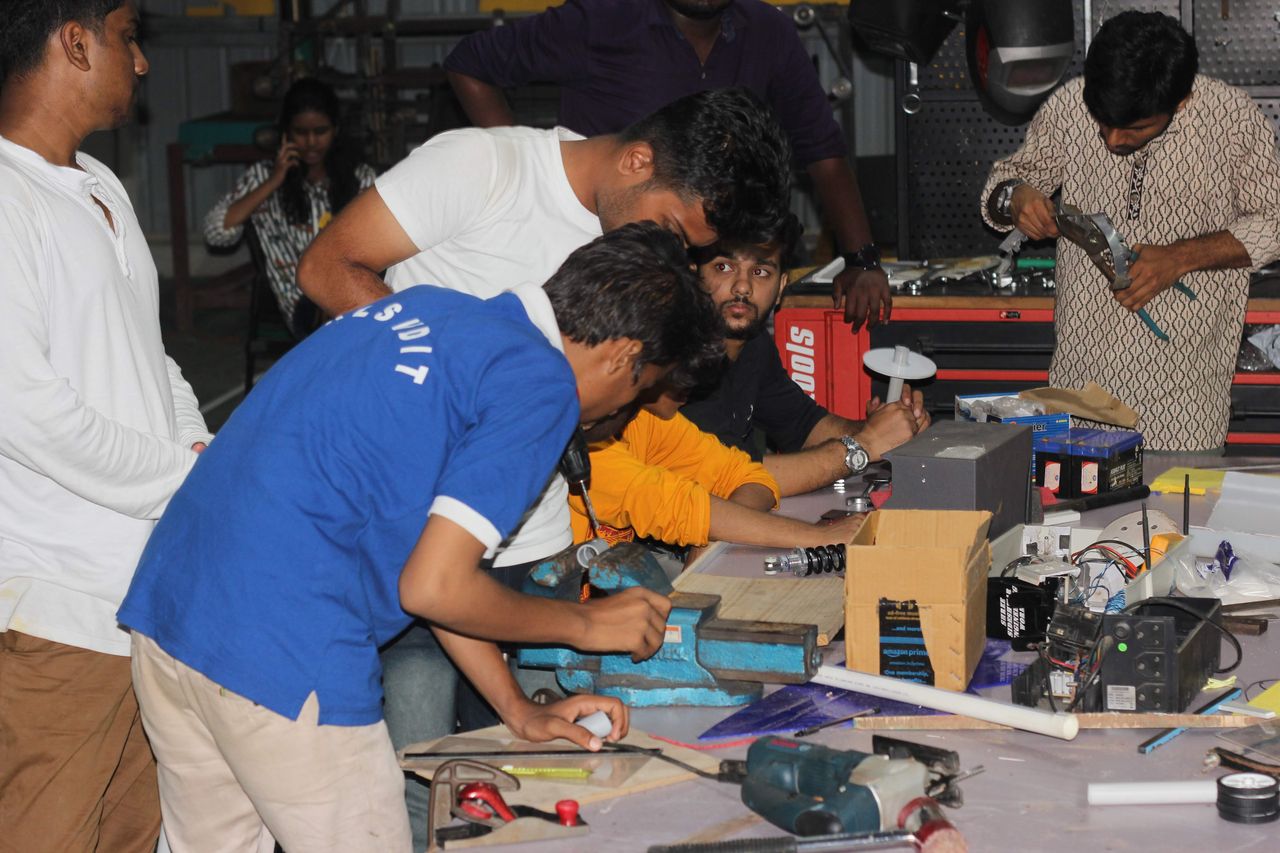 Young makers building a hardware prototype together at a workbench