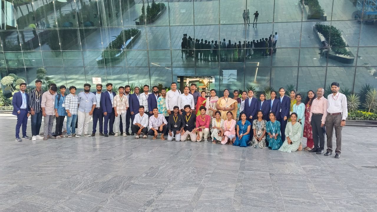 A large group of students and program staff gathered outside a glass-fronted building