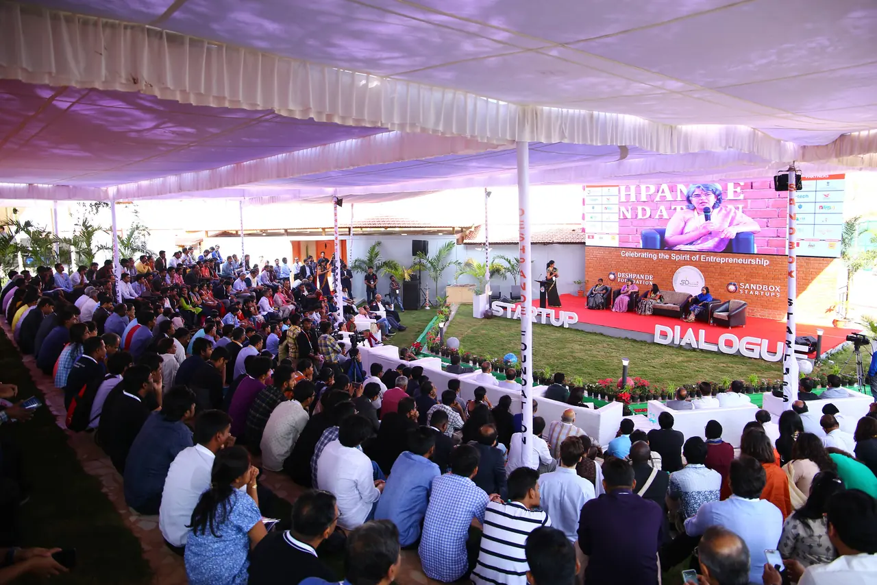 A packed audience under a large tent facing the Startup Dialogue stage
