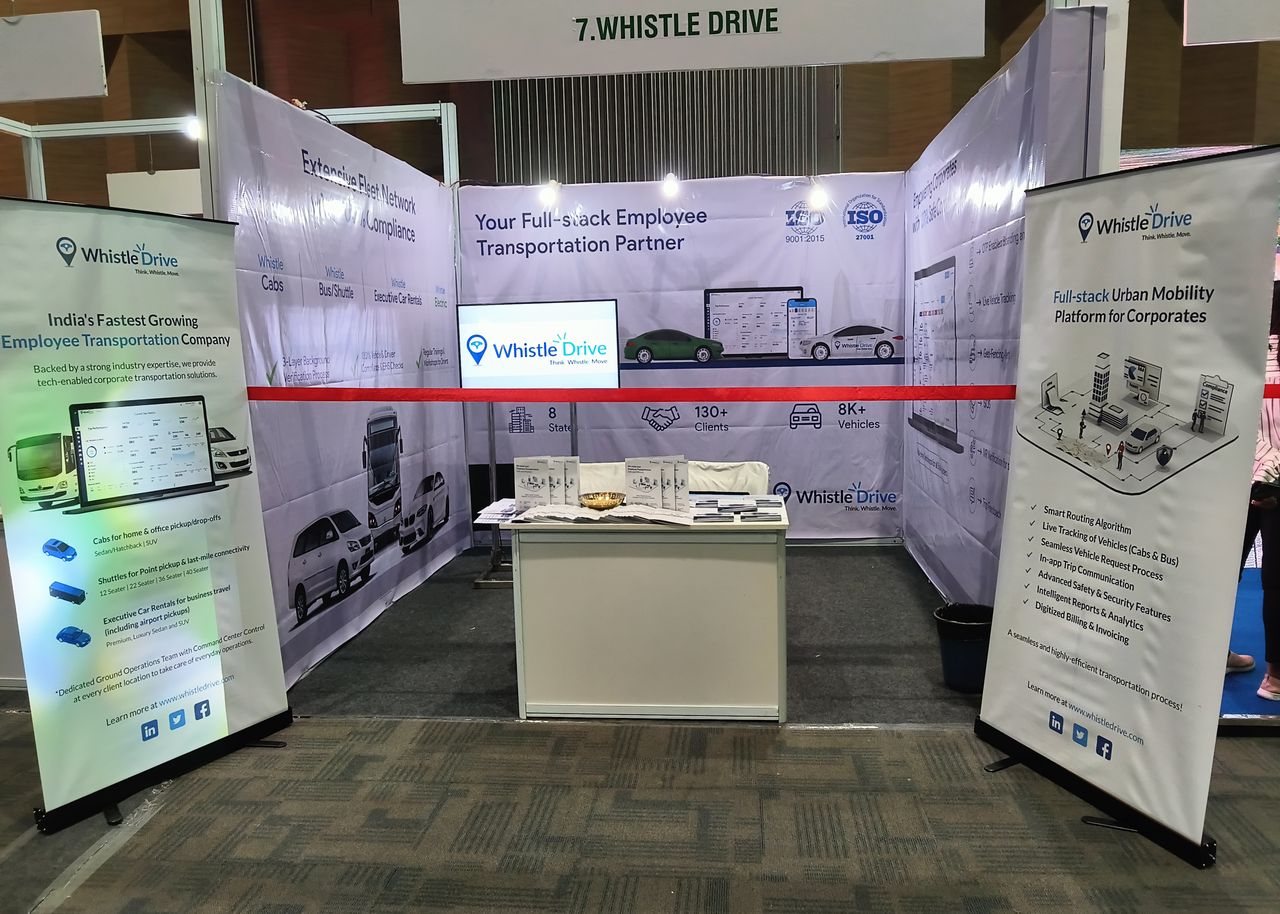 WhistleDrive exhibition stall with branded panels describing employee transportation services